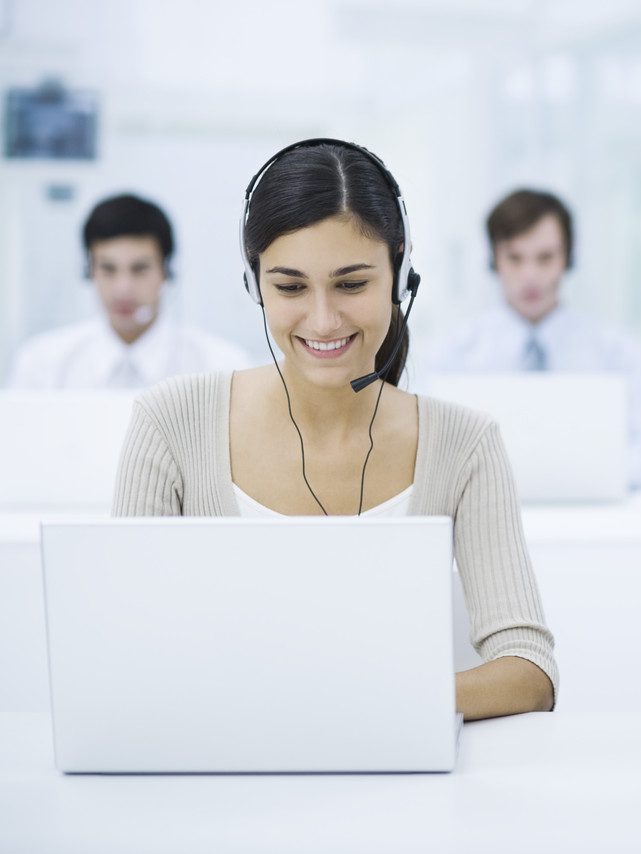 Frau mit Headset vor einem Laptop